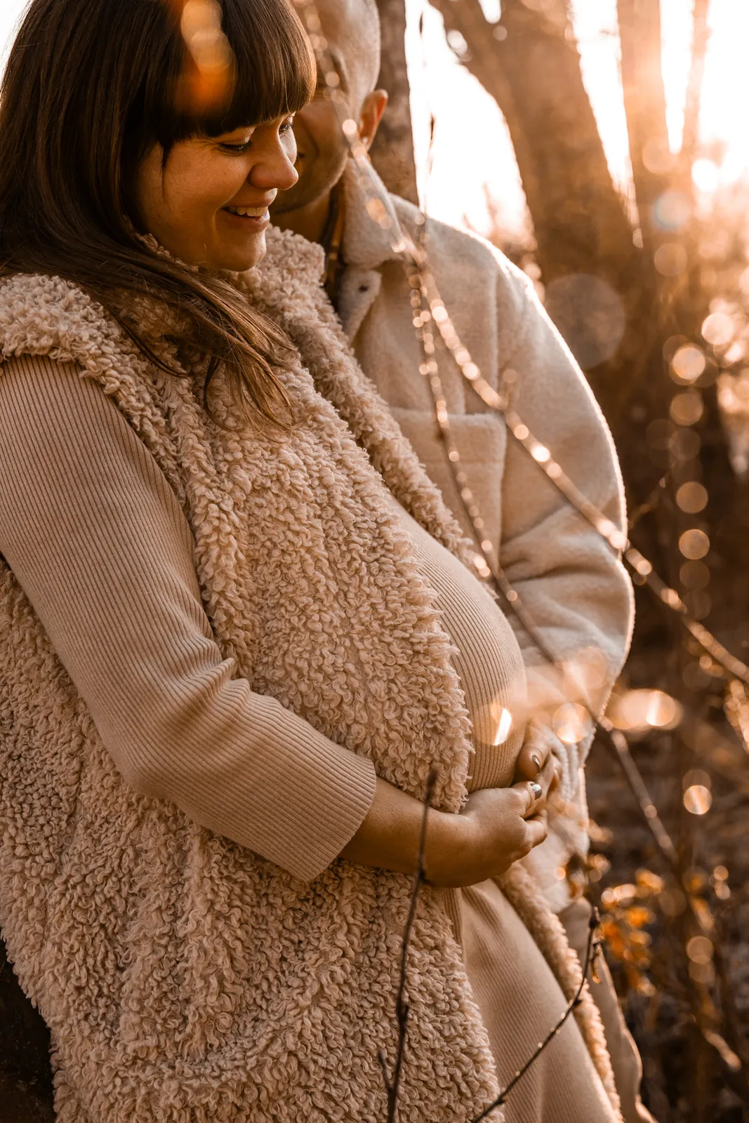 Przyszła mama czule obejmuje brzuszek rękami, w tle wschód słońca