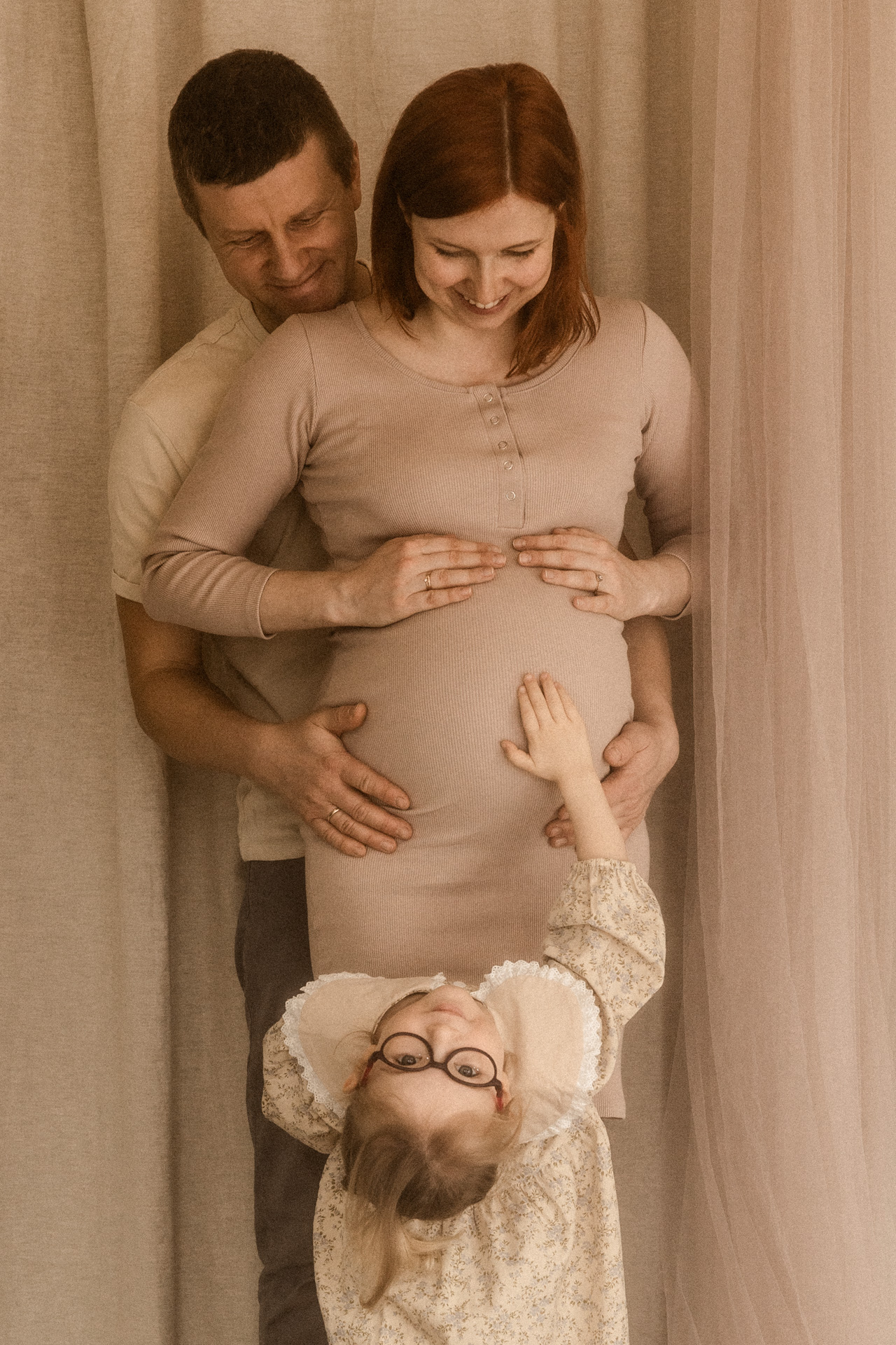 Przyszli rodzice z córką podczas rodzinnej sesji brzuszkowej w studiu fotograficznym
