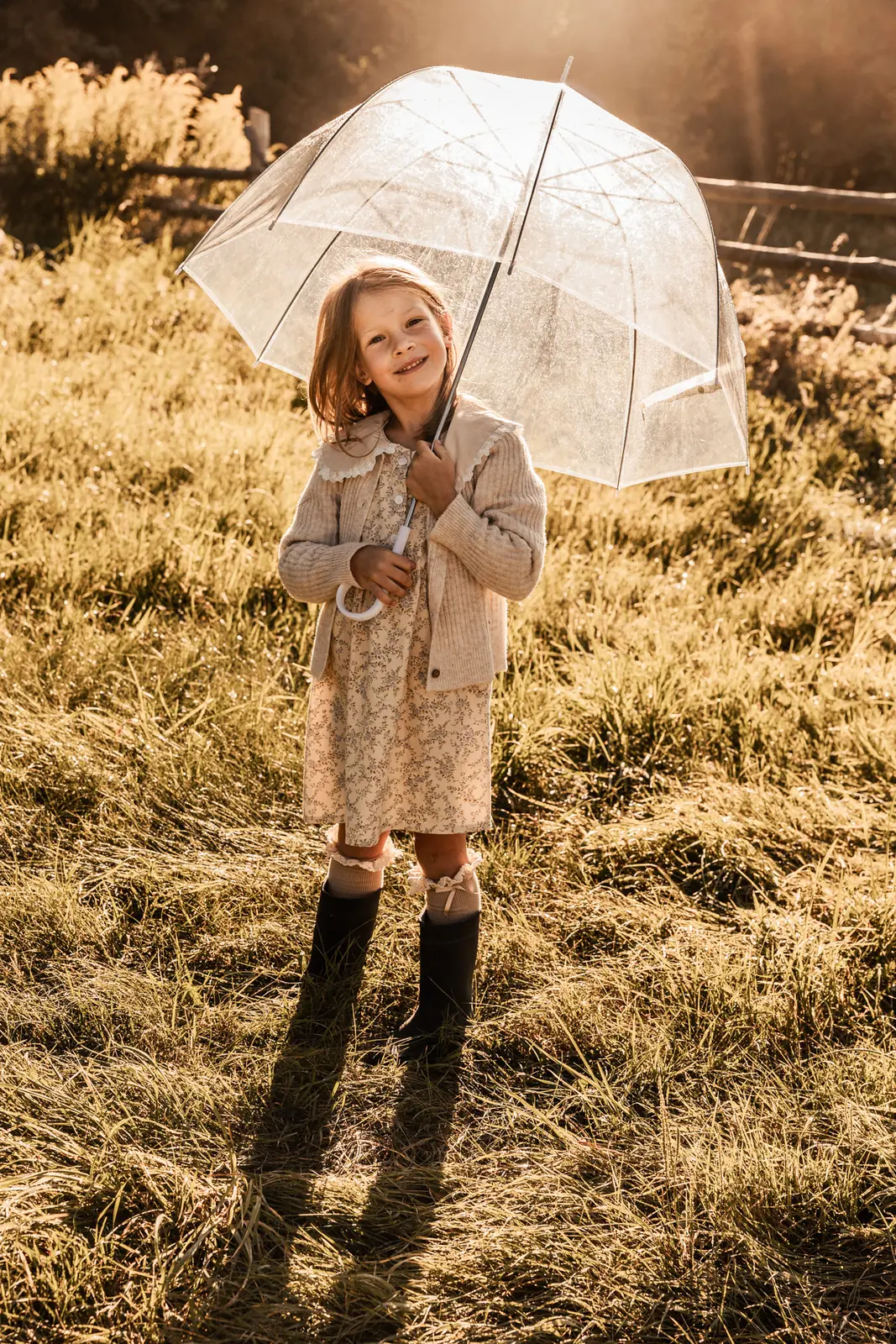 Dziewczynka z parasolem podczas zabawy na łące w plenerze o wschodzie słońca