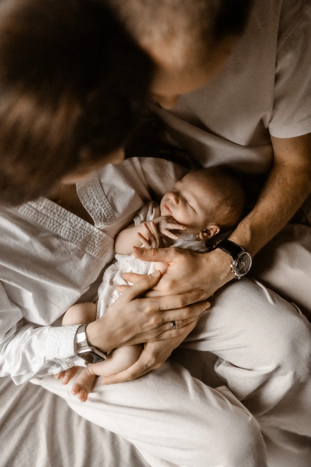 Naturalne zdjęcie rodziców przytulających śpiącego noworodka