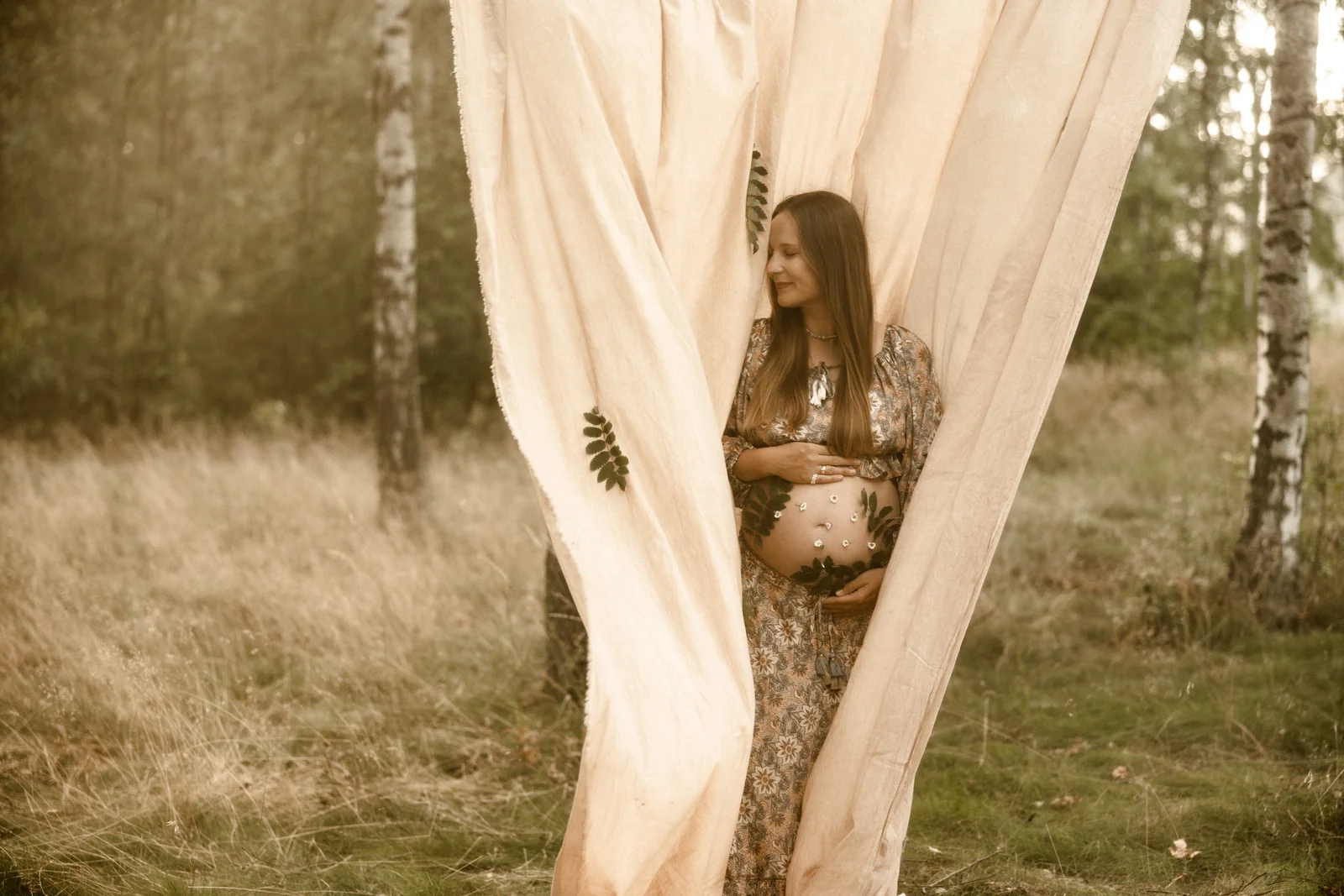 Przyszła mama otulona tkaniną w podczas plenerowej sesji w lesie pod Poznaniem