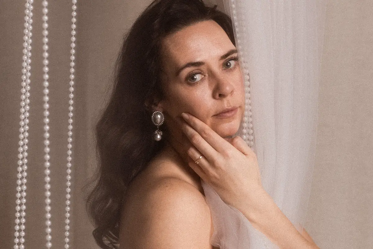 Artystyczny portret kobiecy. Kobieta owinięta w delikatny materiał, w tle korale.