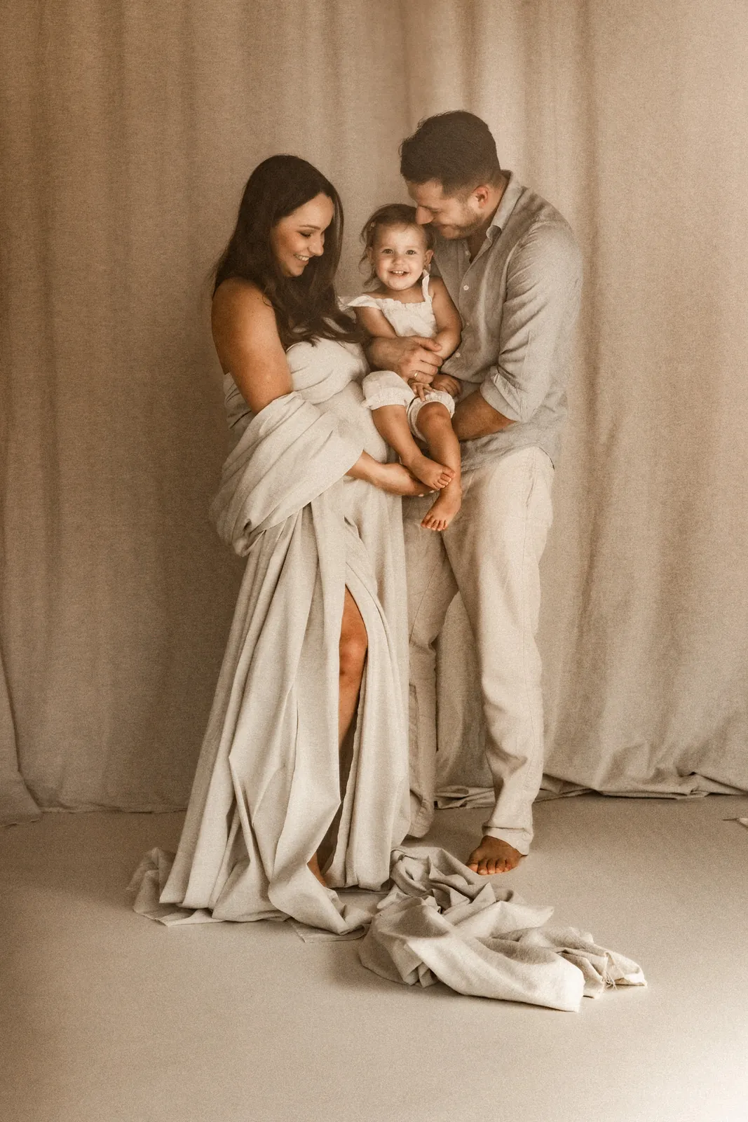 Wspólne zdjęcie przyszłych rodziców i ich dziecka w minimalistycznym studiu