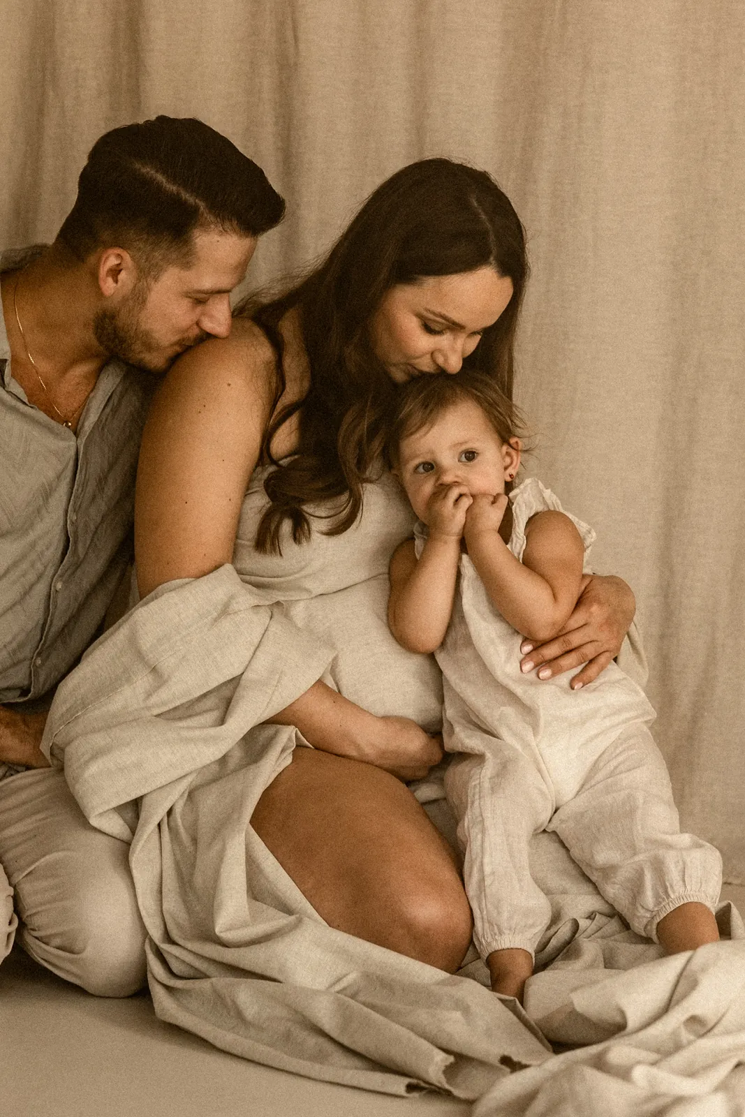 Bliskie ujęcie rodziny, tata całuje mamę, mama córkę w głowę