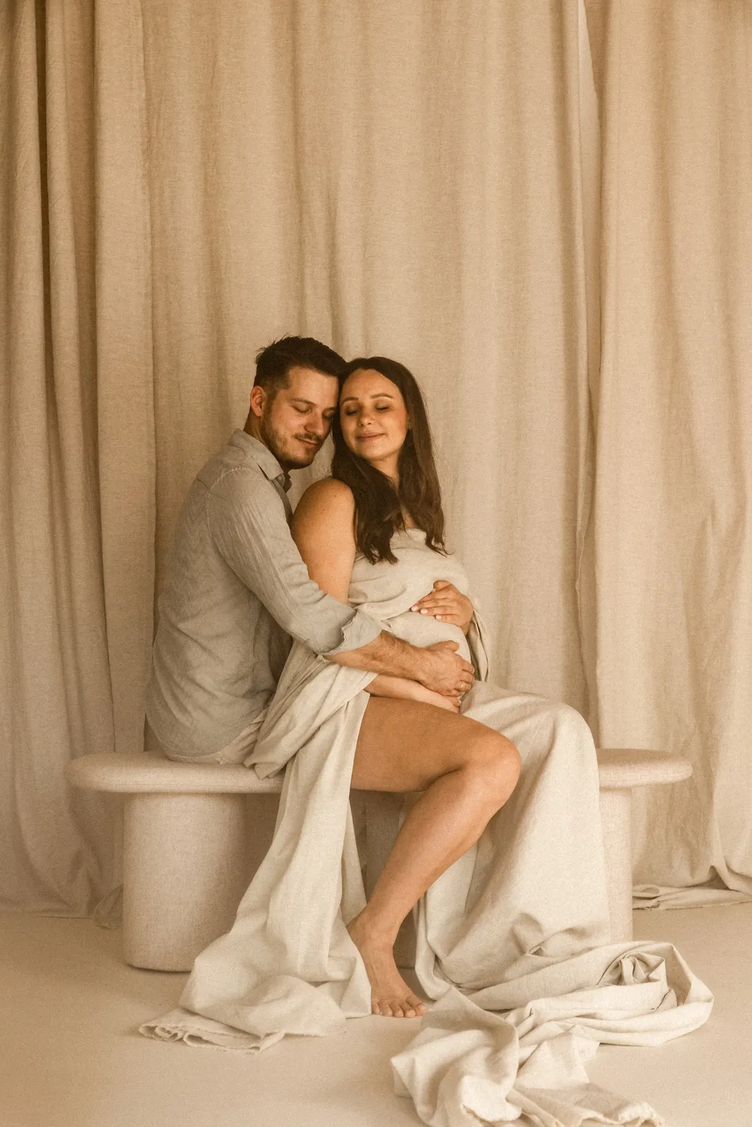 Kobieta w ciąży z partnerem, który czule ją obejmuje podczas sesji brzuszkowej