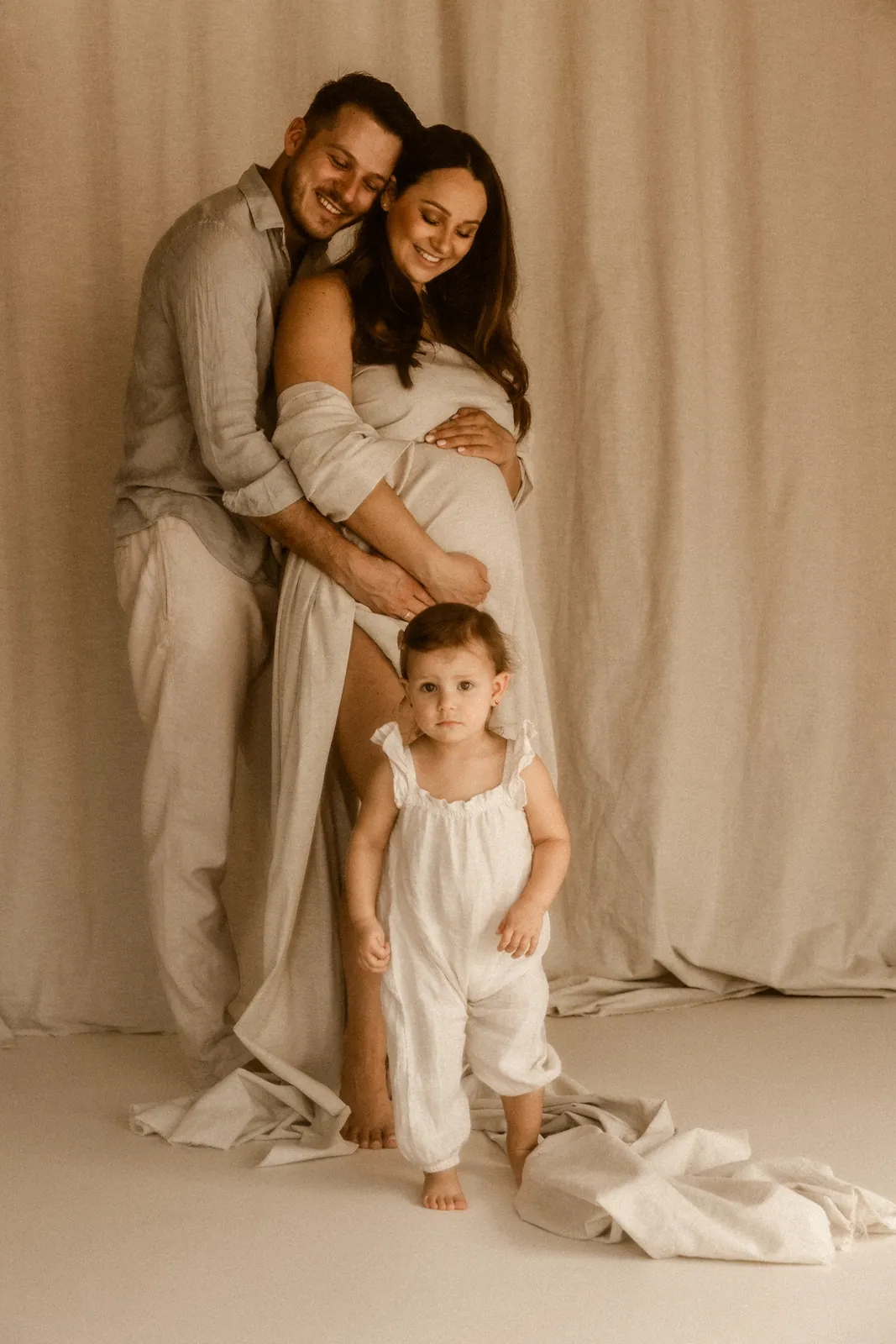 Tata obejmuje mamę i córkę podczas rodzinnej sesji ciążowej