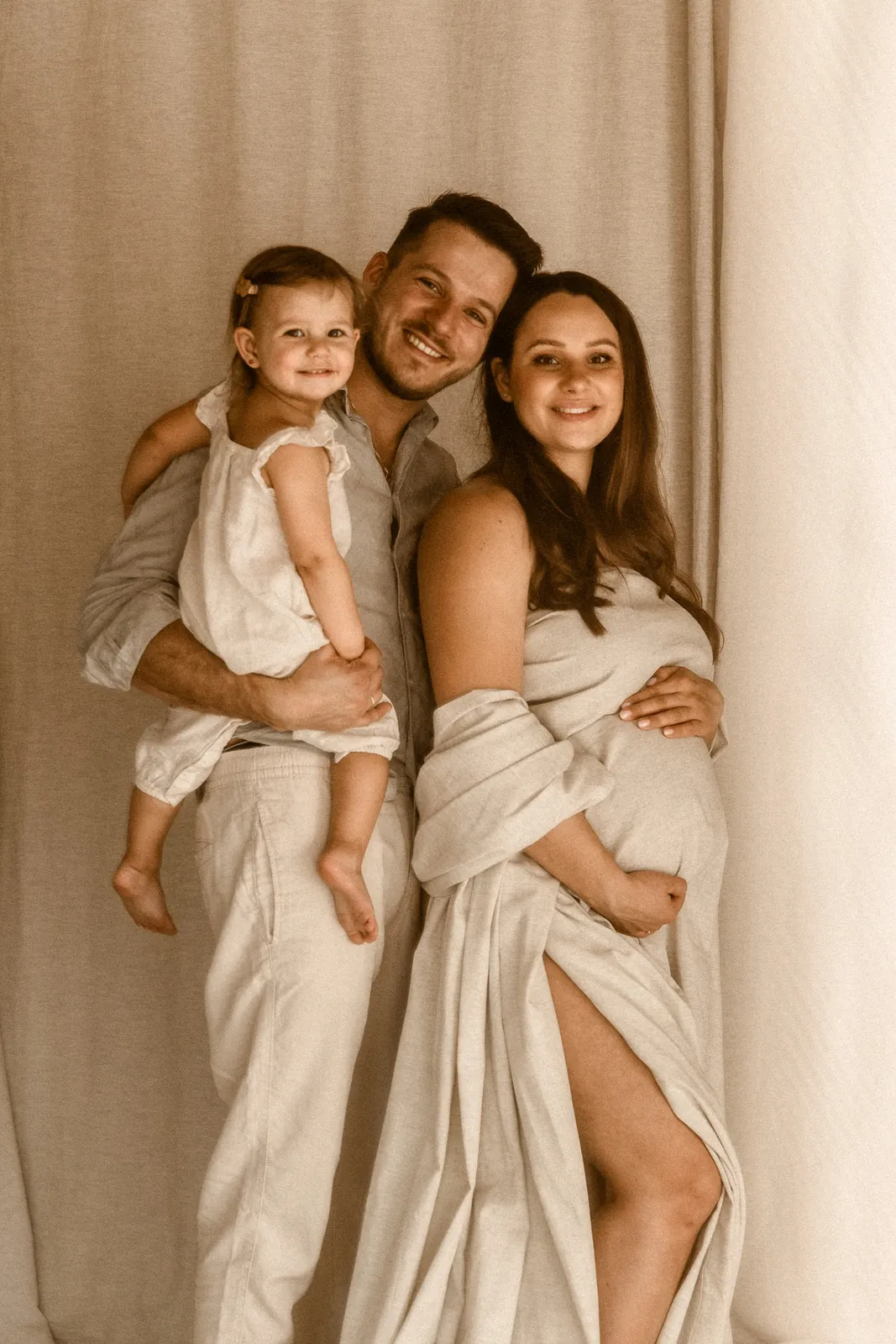 Rodzinny portret przyszłych rodziców i ich starszej córki podczas brzuszkowej sesji zdjęciowej