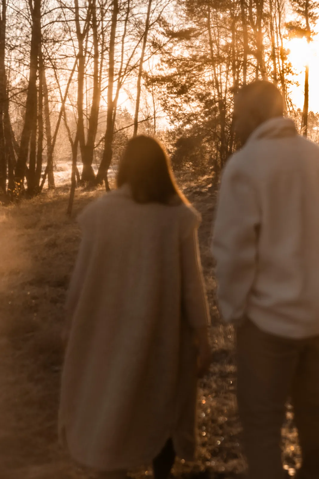 Przyszli rodzice spacerują wśród drzew w jesiennej scenerii