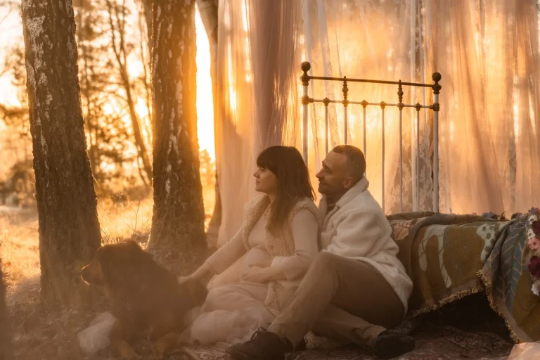 Portret kobiety i jej partnera podczas jesiennej sesji ciążowej o wschodzie słońca w towarzystwie psa