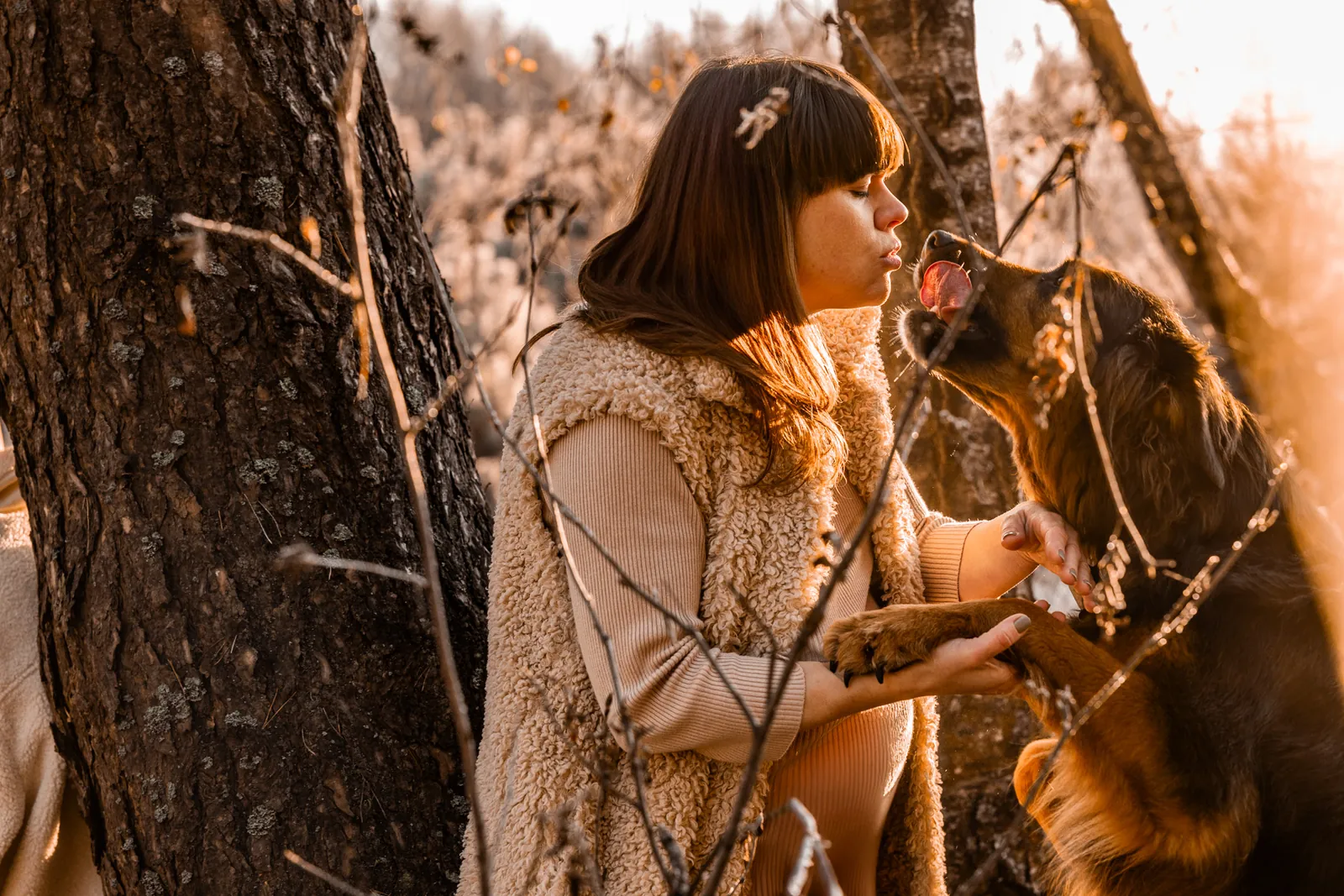 Kobieta w ciąży na spacerze w jesiennej scenerii z jej czworonożnym przyjacielem