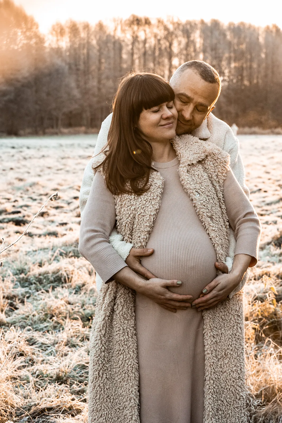 Minimalistyczny kadr przyszłych rodziców czule obejmujących dłońmi brzuszek mamy w jesiennej sesji