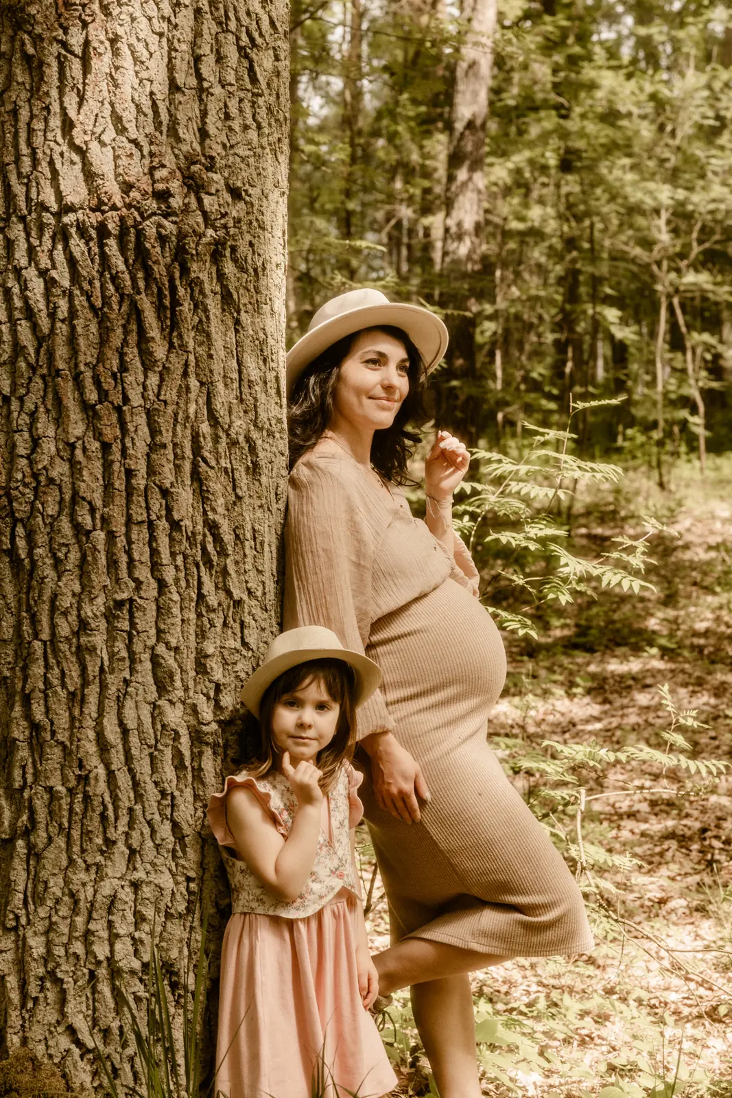 Kobieta w ciąży z starszą córka podczas naturalnej sesji zdjęciowej w lesie
