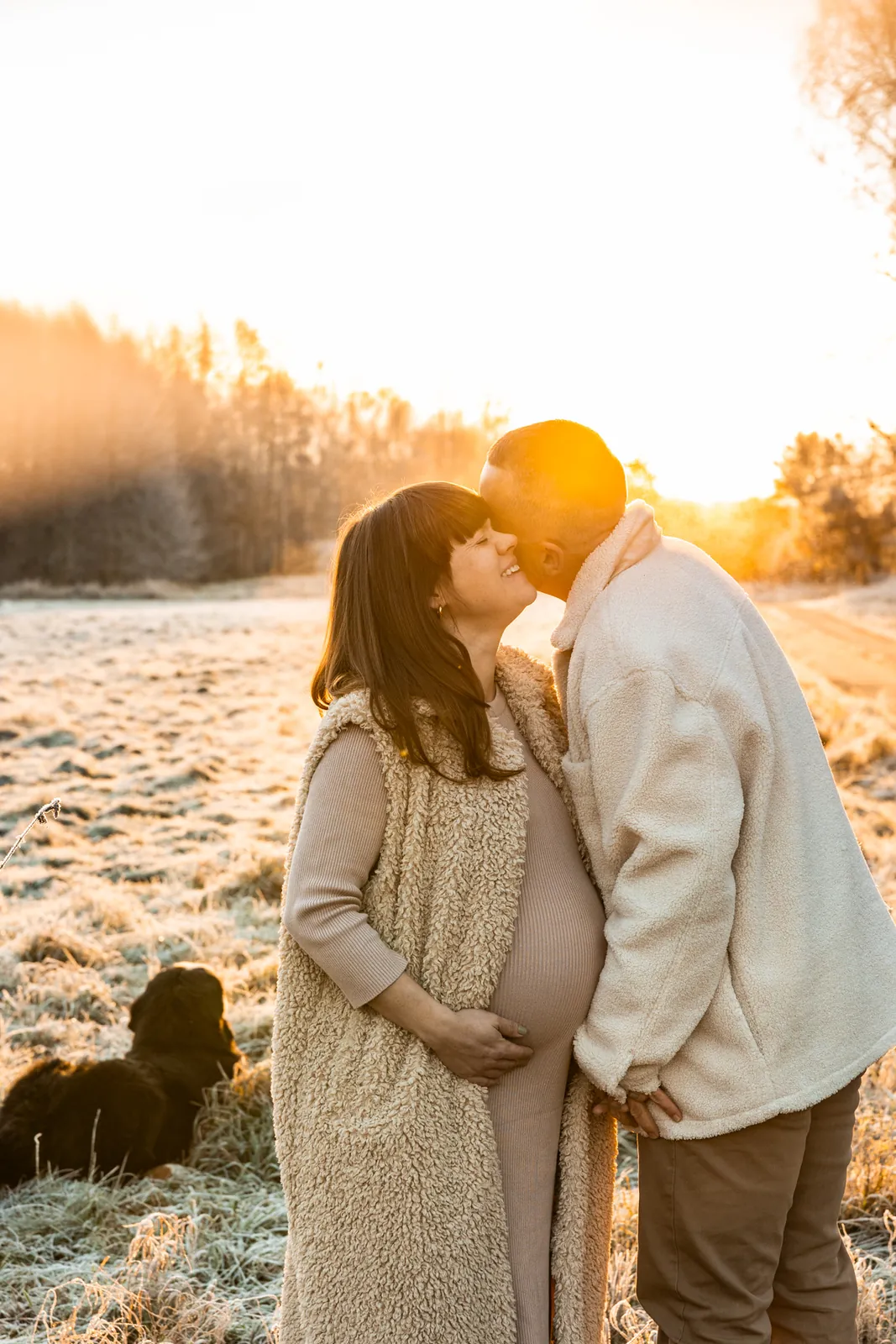 Sesja ciążowa w plenerze o wschodzie słońca. W tle łąka i oznaki nadchodzącej zimy.