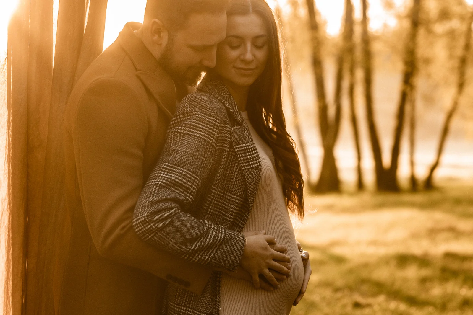 Partner delikatnie obejmuje dłońmi brzuszek przyszłej mamy