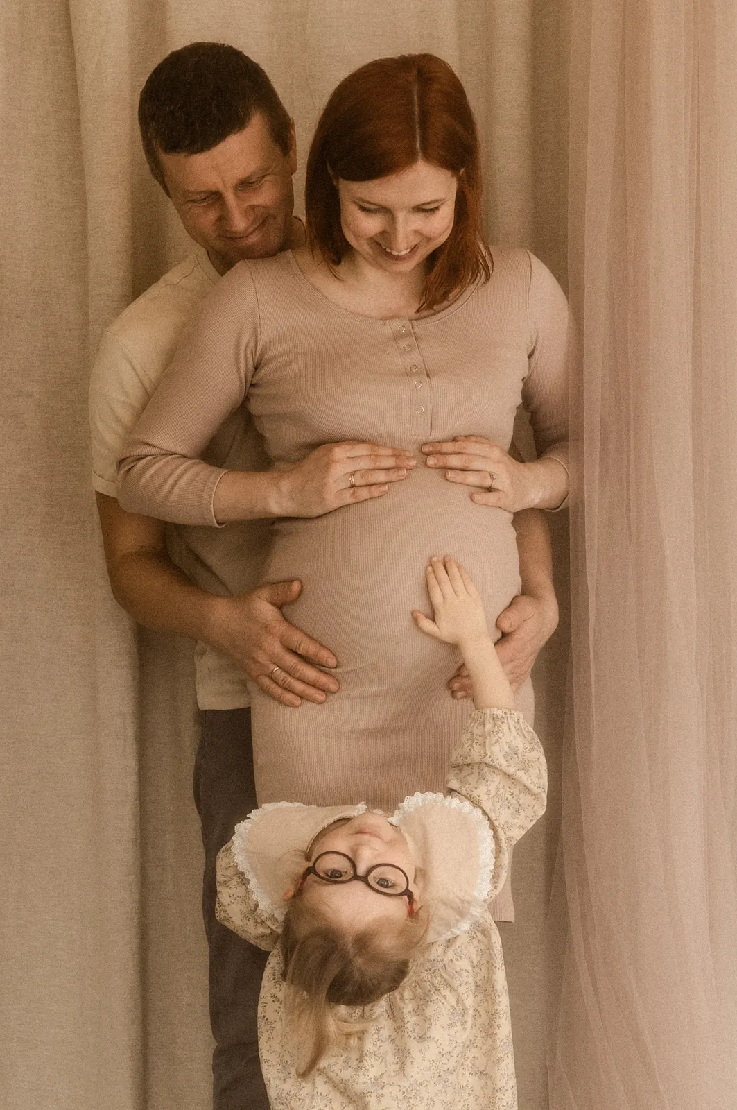 Rodzice z starszym dzieckiem w naturalnym momencie podczas sesji ciążowej w studio fotograficznym