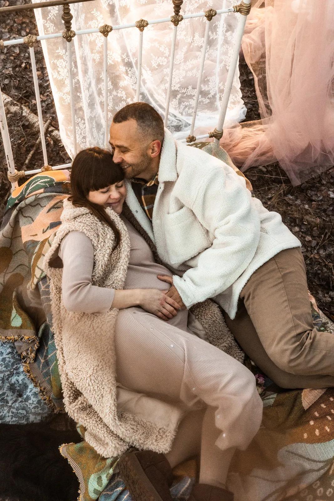 Detale dłoni przyszłych rodziców na brzuszku mamy podczas sesji ciążowej w stylu filmowym