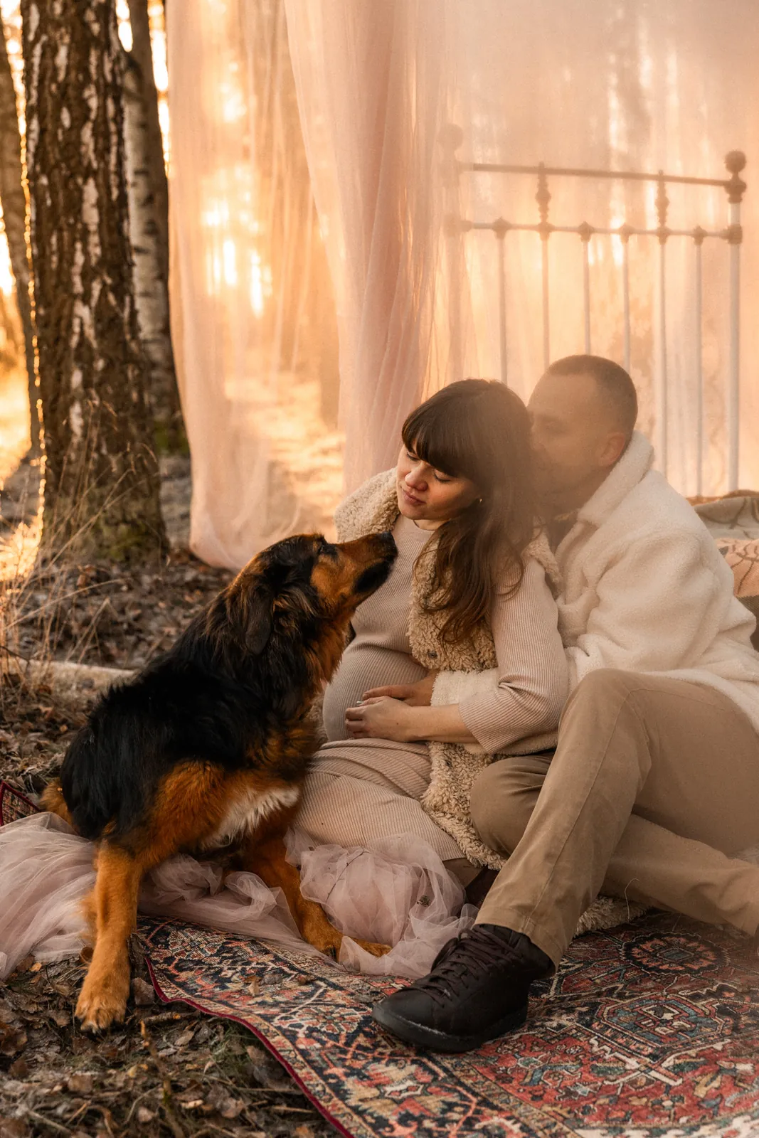 Przyszli rodzice w oczekiwaniu na przyjście dziecka podczas jesiennej sesji ciążowej w plenerze w towarzystwie psa