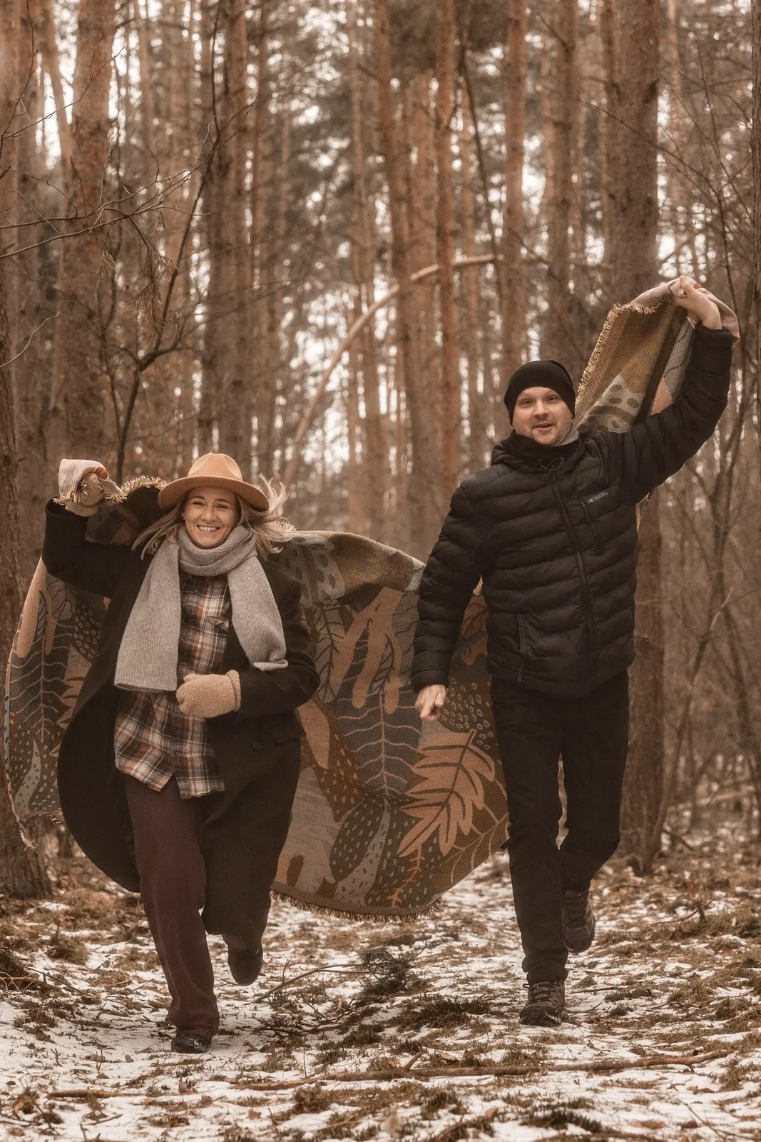 Narzeczeni spacerujący po lesie podczas sesji narzeczeńskiej w Poznaniu, w tle zimowa sceneria