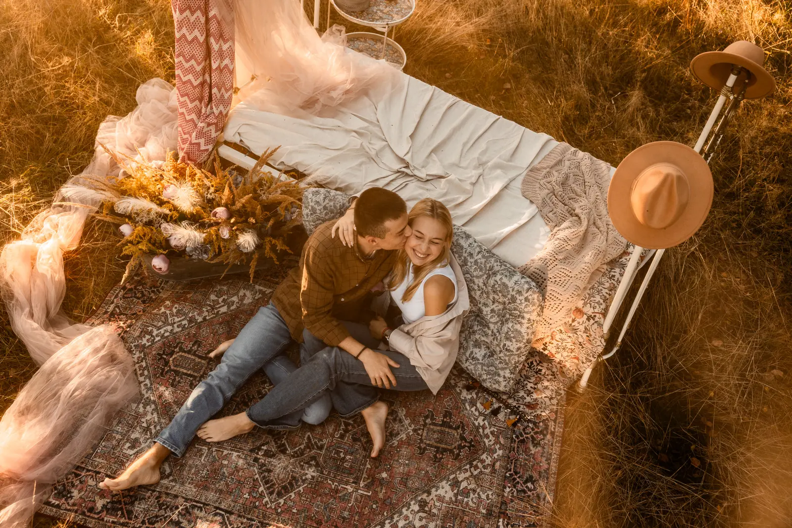 Chłopak czule całuje ukochaną, w tle stylowa aranżacja i sielankowy krajobraz