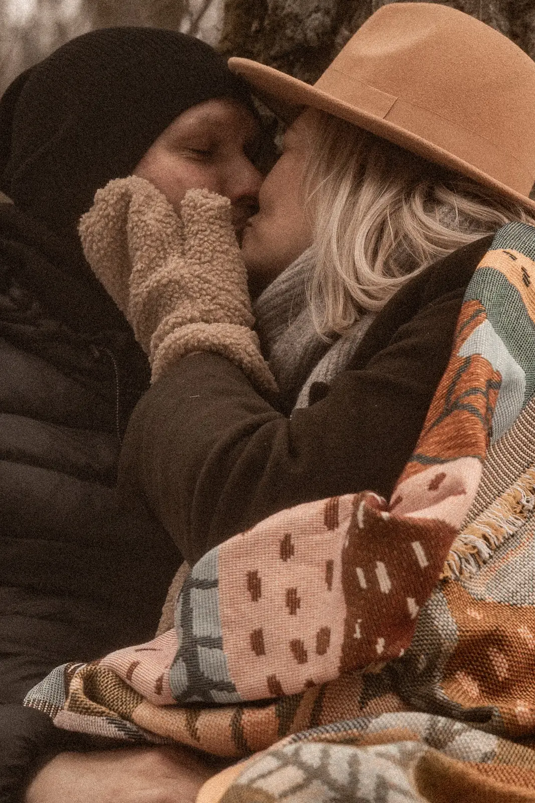 Zbliżenie na przytulającą się parę narzeczonych, która skrada pocałunek w środku lasu