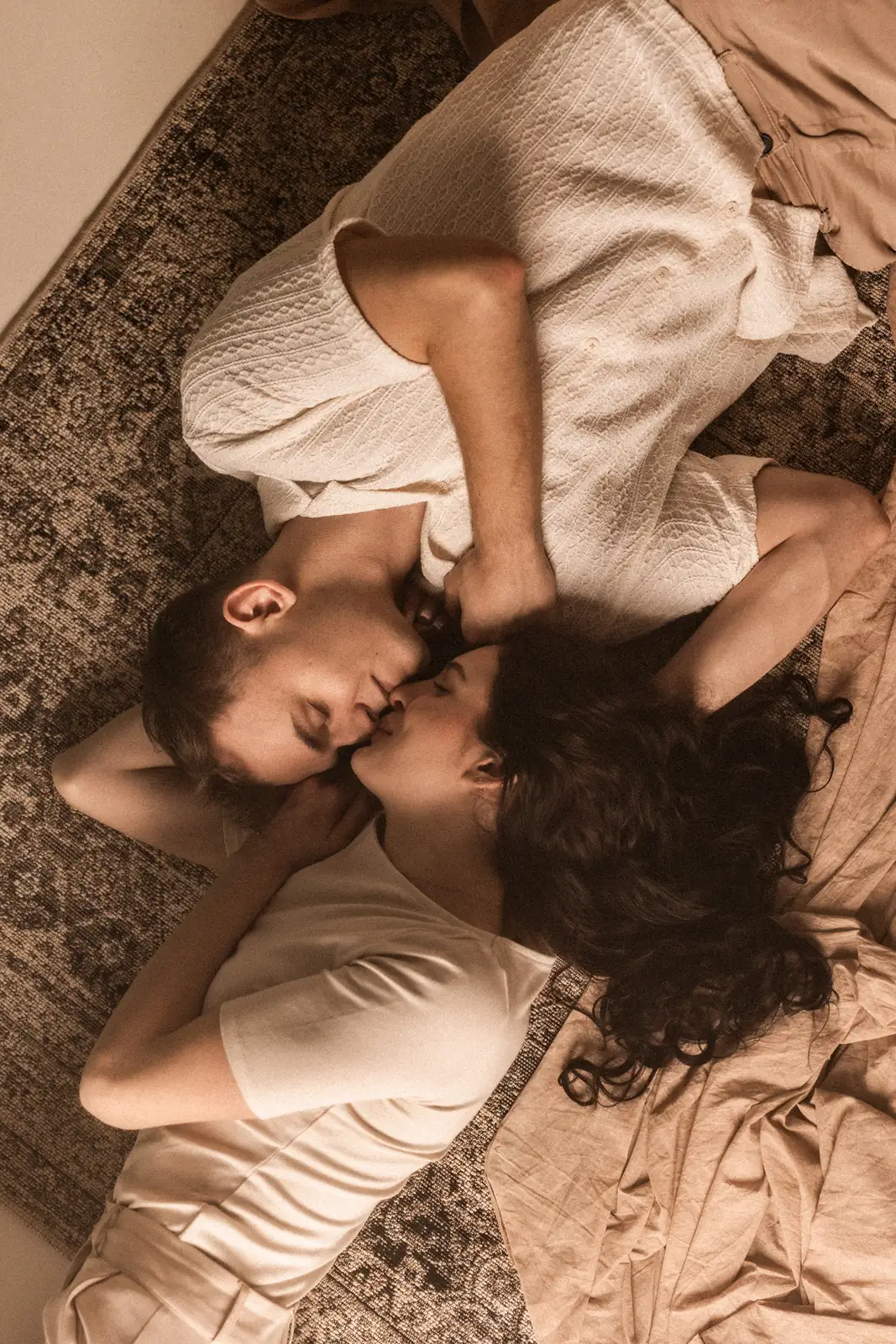 Zakochana para leży na dywanie przytulona do siebie twarzą podczas sesji zdjęciowej w studiu