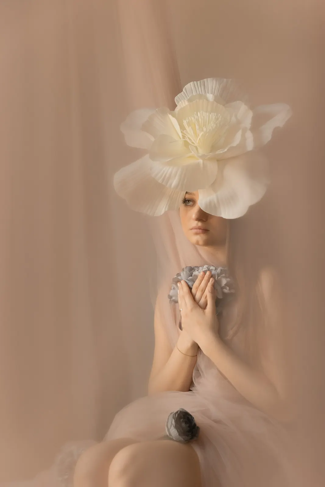 Artystyczny portret kobiety - duży biały kwiat zdobi kobiece włosy. W tle tiule, kwiaty i naturalne światło