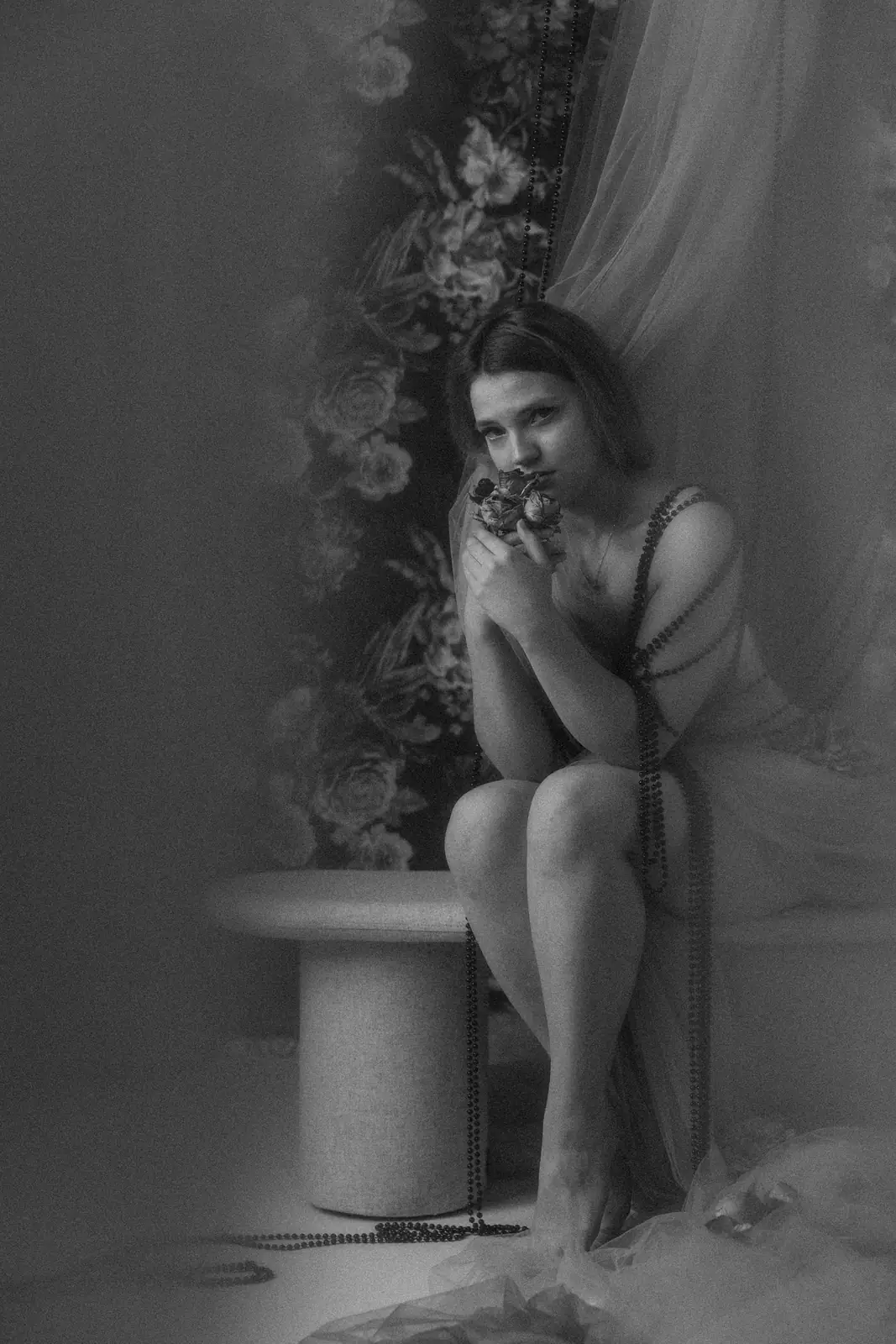 Czarno-biała portretowa sesja kobieca na artystycznym tle, w tle tło kwiatowe, korale i tiul