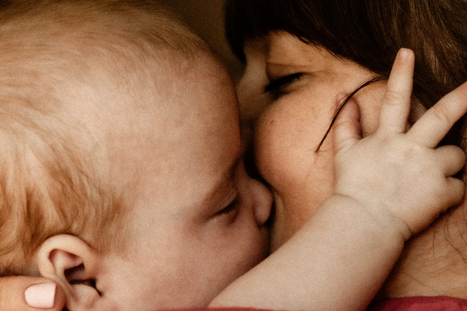 Mama czule przytula i całuje niemowlę podczas sesji domowej