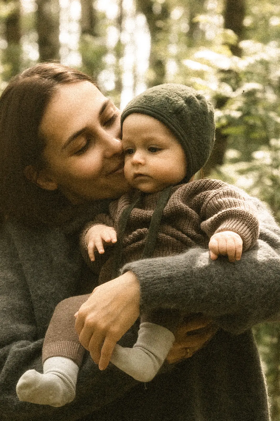 Mama trzyma noworodka na rękach podczas wyjątkowej plenerowej sesji zdjęciowej w leśnej scenerii pod Poznaniem