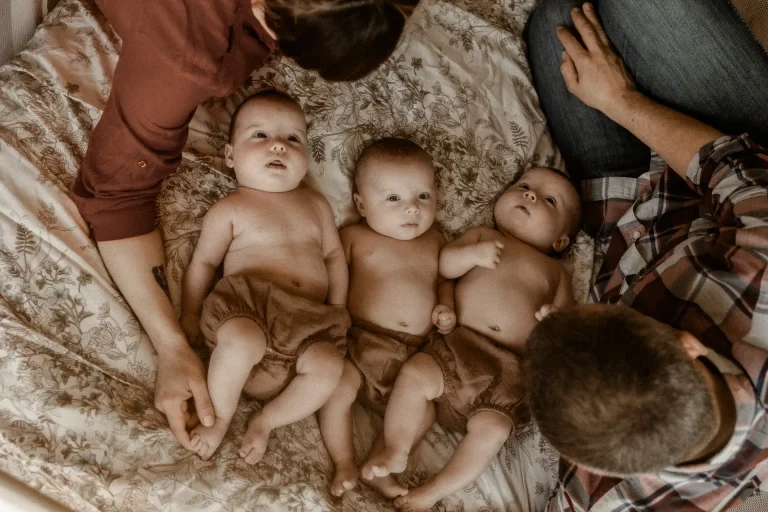 Lifestyle fotografia niemowlęca trójki córeczek z rodzicami w domu