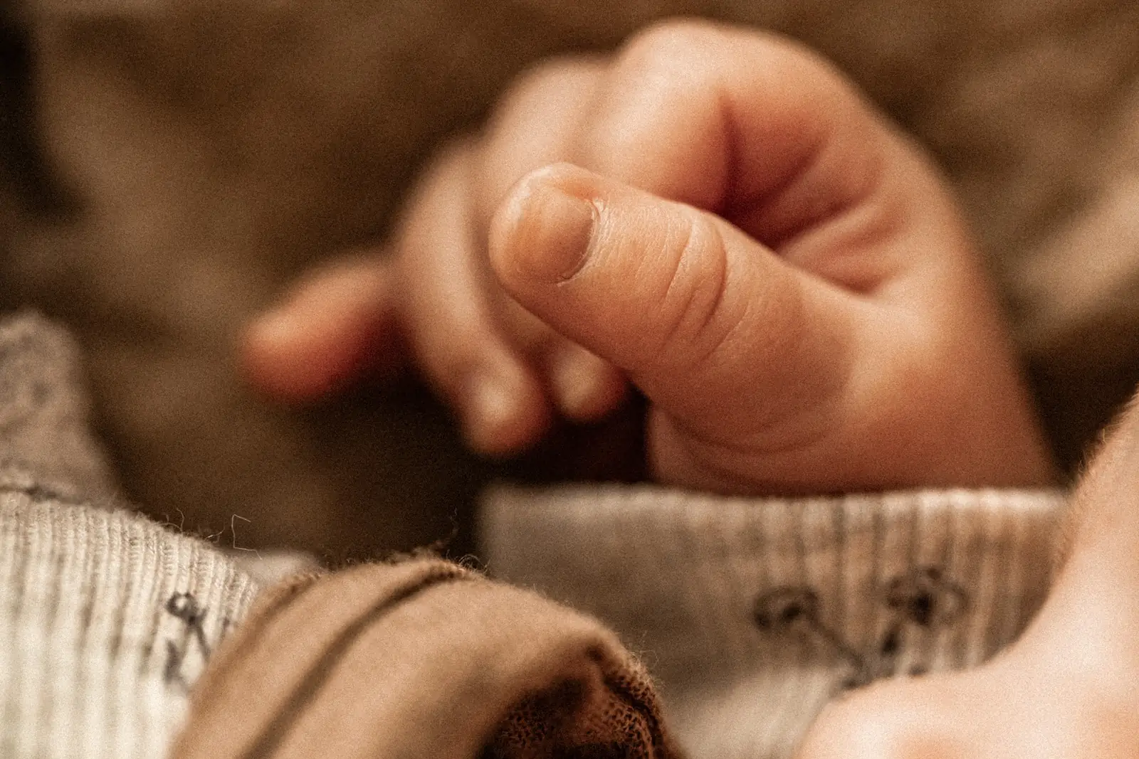 Zbliżenie na rączkę noworodka podczas naturalnej sesji zdjęciowej w domu rodzinnym