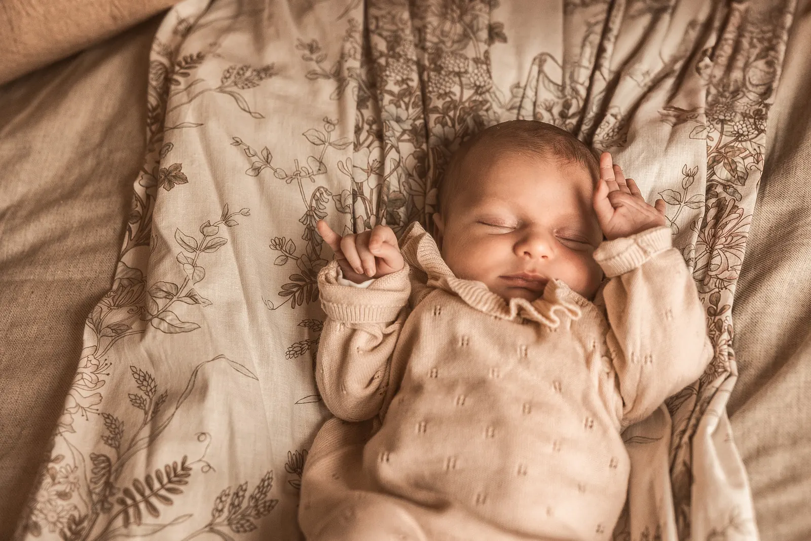 Noworodek śpiący na jasnym kocu podczas sesji noworodkowej