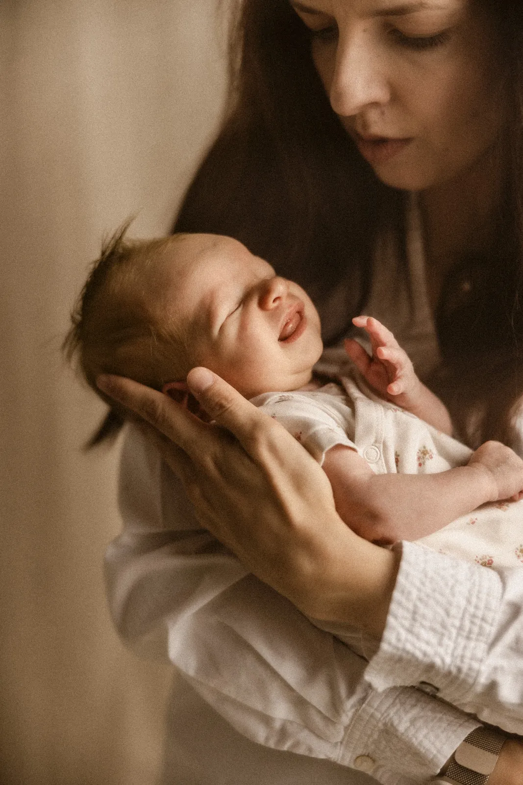 Mama przytula na rękach maleńko dziecko podczas sesji w studiu w Poznaniu