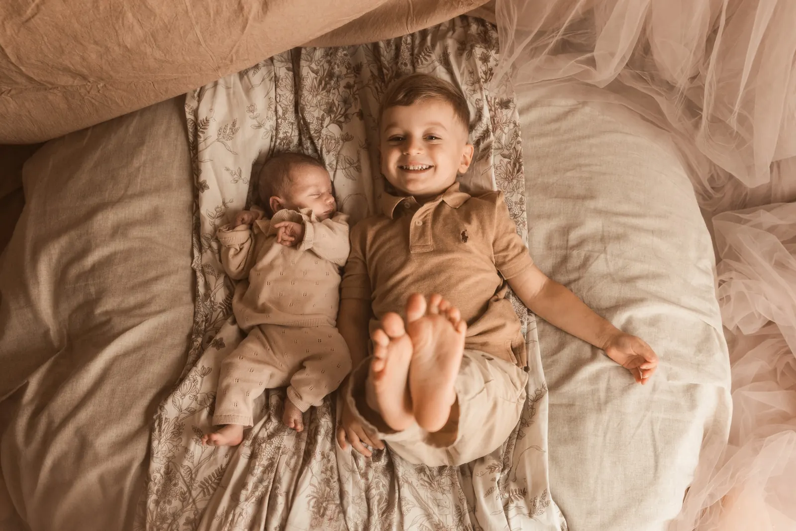 Noworodek leżący obok starszego rodzieństwa, kolorystyka w stylu boho