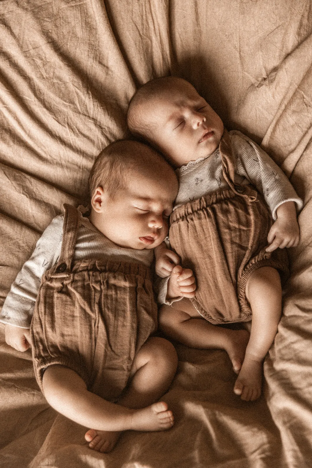 Śpiące rodzeństwo noworodków przytulonych do siebie podczas spokojnej sesji noworodkowej