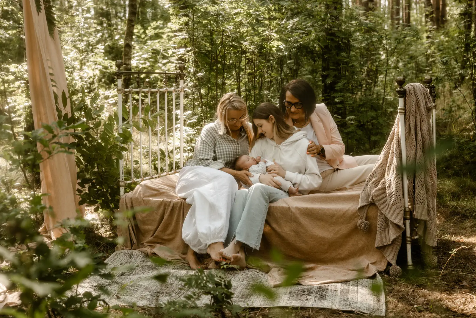 Wielopokoleniowe zdjęcie czterech kobiet na jednym kadrze - córeczka, mama, babcia i prababcia podczas sesji noworodkowej w plenerze