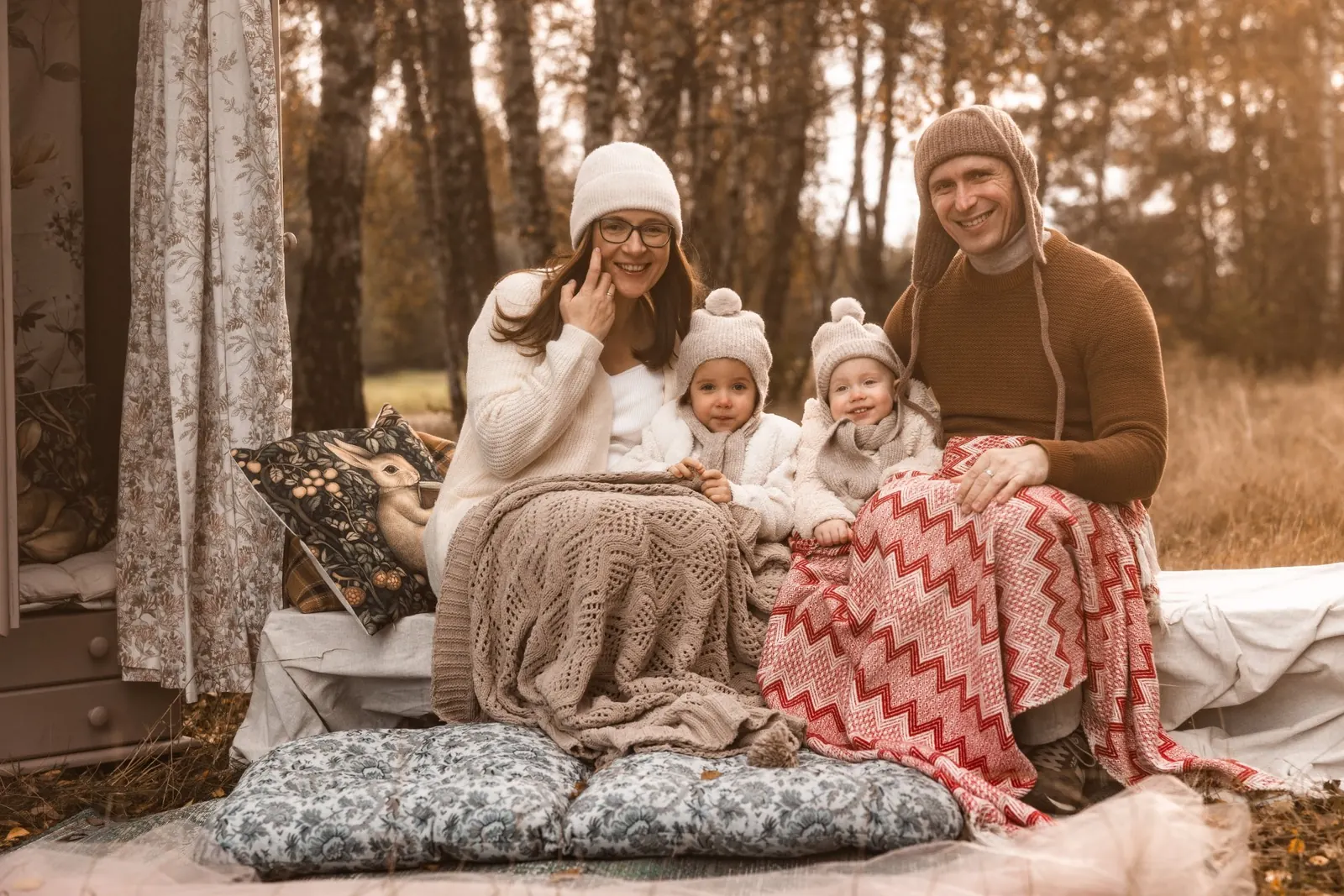 Naturalne portrety rodzinne wykonane podczas sesji w autentycznej scenerii. Rodzice przytulają dzieci. W tle las i łąka.