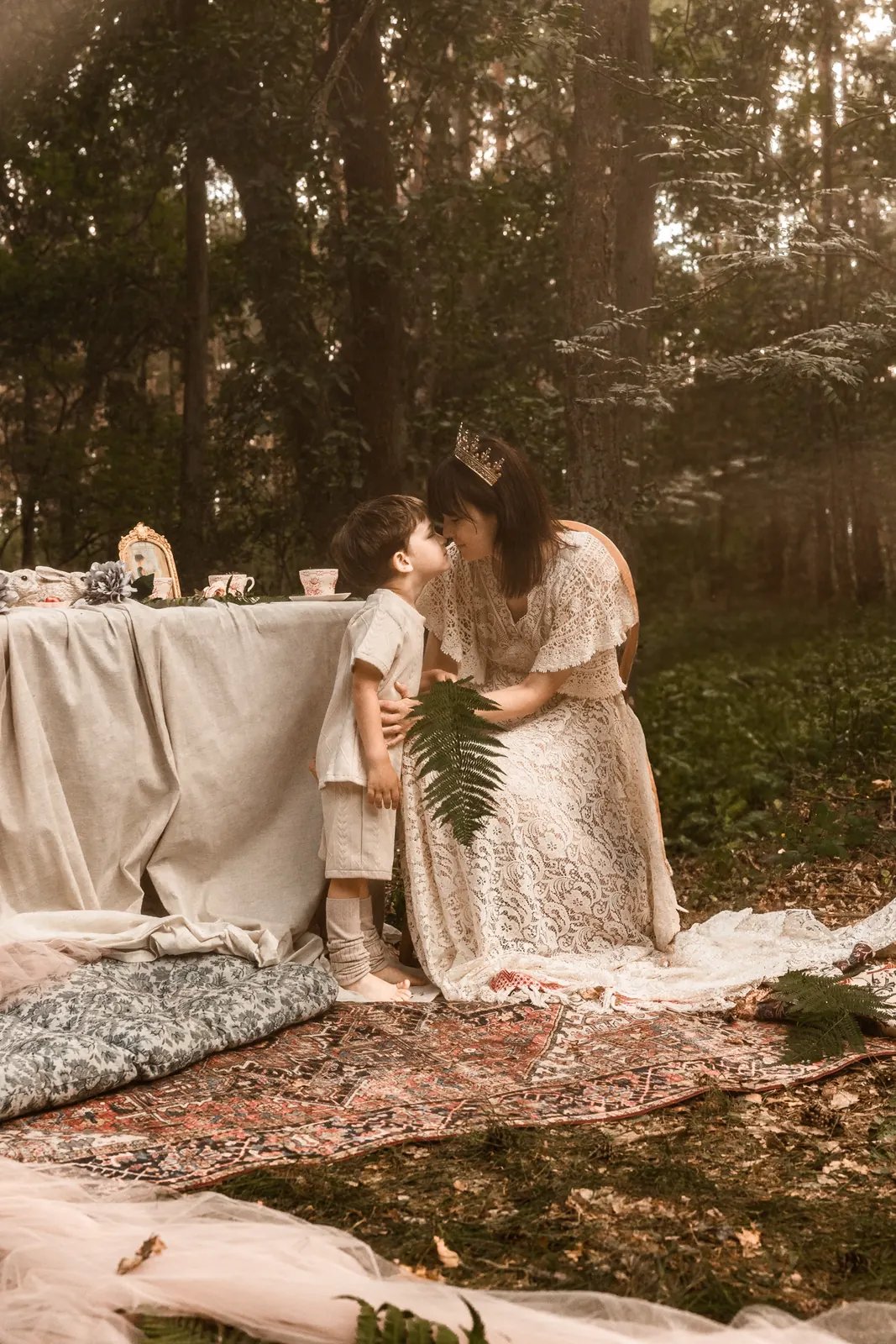 Plenerowe zdjęcie mamy z dzieckiem w aranżowanej scenerii na tle lasu