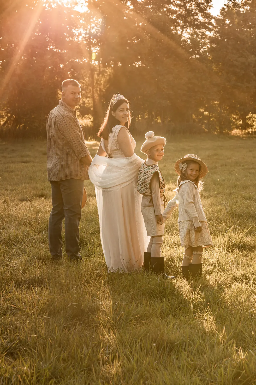 Roześmiana rodzina podczas naturalnej sesji w plenerze. Promienie słoneczne przebijają się przez drzewa i oświetlają modeli.