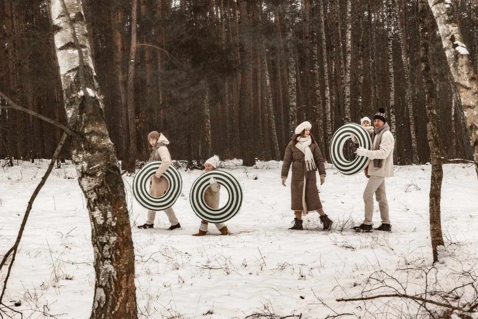 Rodzina spaceruje po śniegu przez las podczas zimowe sesji zdjęciowej