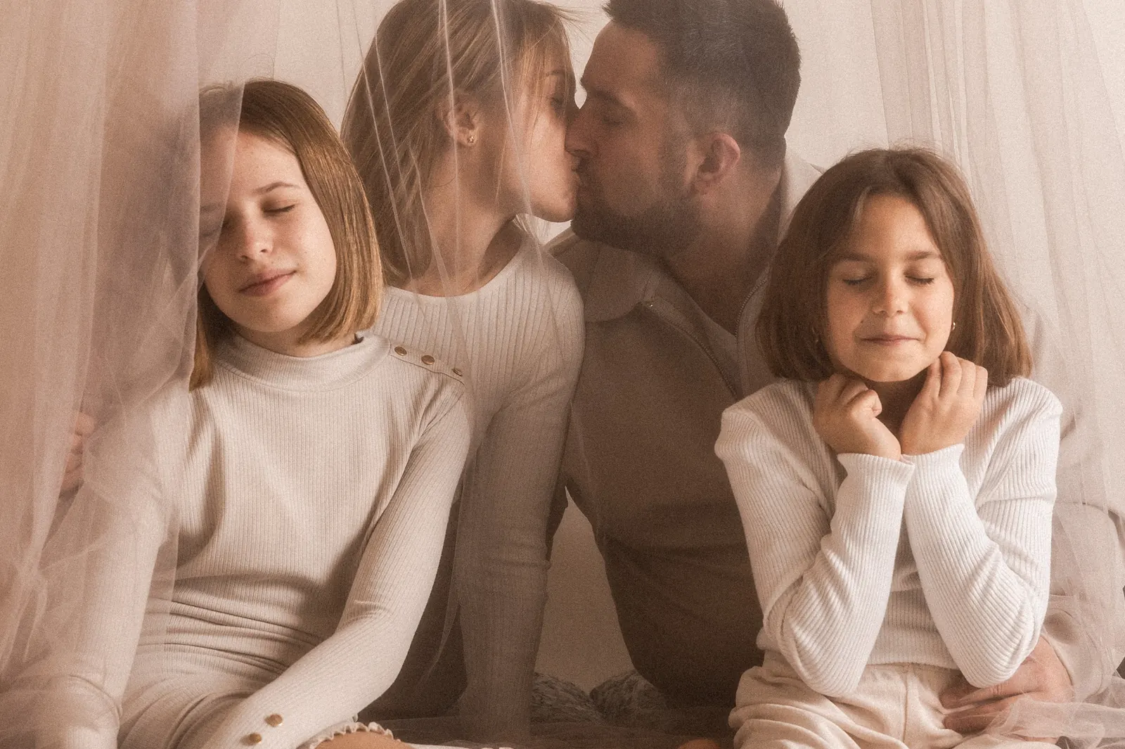 Spontaniczny moment z lifestylowej rodzinnej sesji zdjęciowej w studiu, w tle minimalistyczne tło.