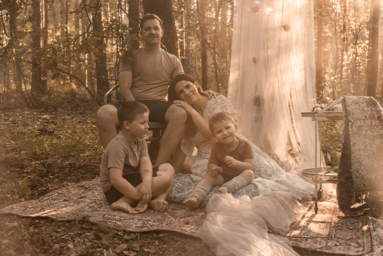 Rodzinna sesja zdjęciowa rodziców z dziećmi w naturalnym otoczeniu lasu, w tle drzewa, kompozycja autorska i naturalne światło.