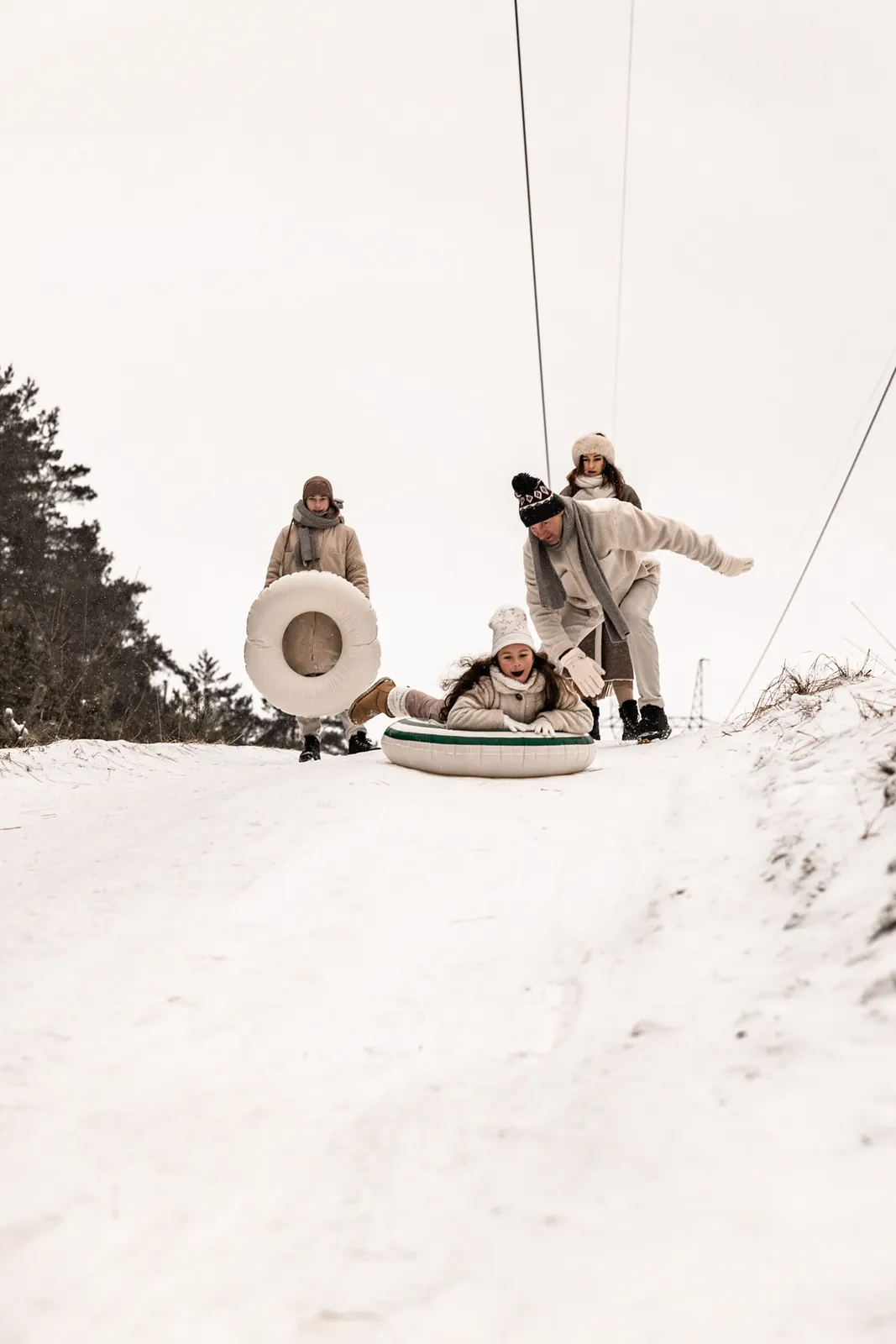 Tata pomaga rozpędzić się na śnieżnej górce córce, która zjeżdża z górki podczas śnieżnej zabawy