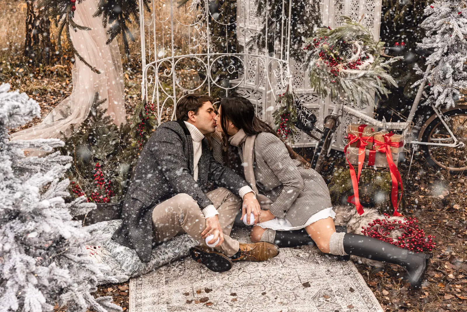 Para podczas pocałunku w trakcie bożonarodzeniowej sesji zimowej, w tle śnieg i oryginalne ozdoby świąteczne