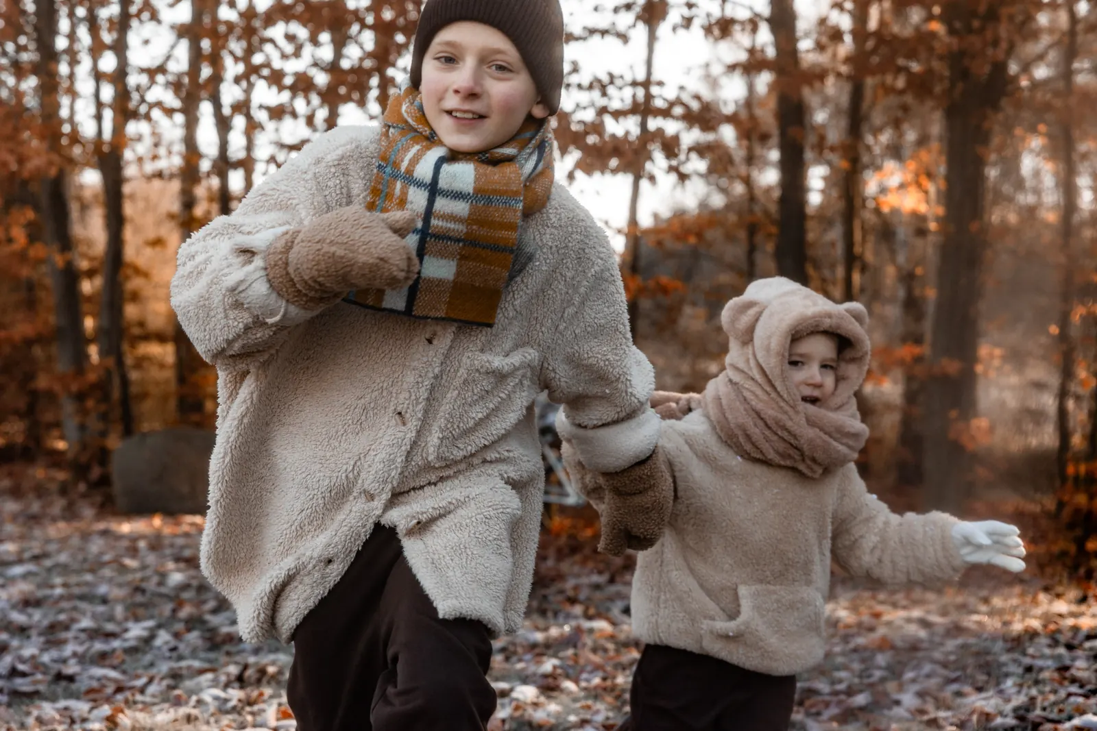 Dzieci tańczą w lesie podczas zimowej sesji zdjęciowej w plenerze