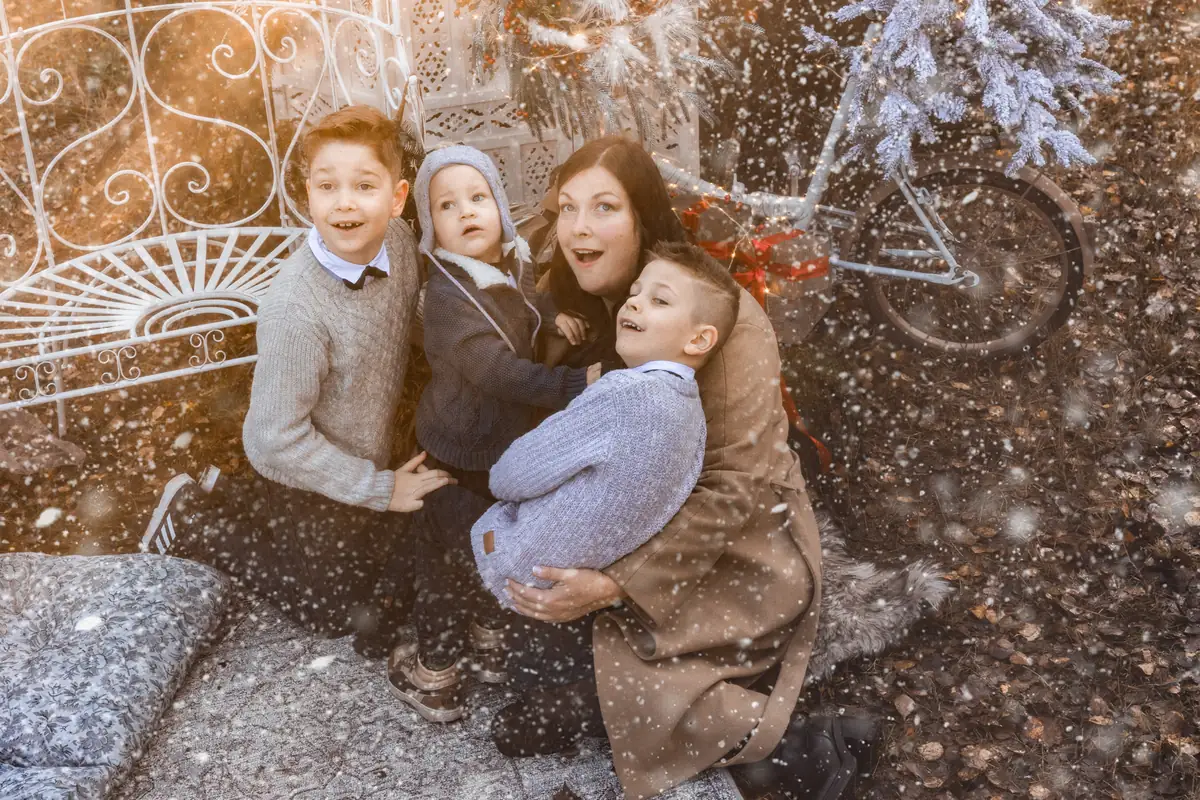 Rodzina w magicznym kadrze - dzieci w oczekiwaniu pierwszej gwiazdki, w tle rower świąteczny z choinką zamiast sanek