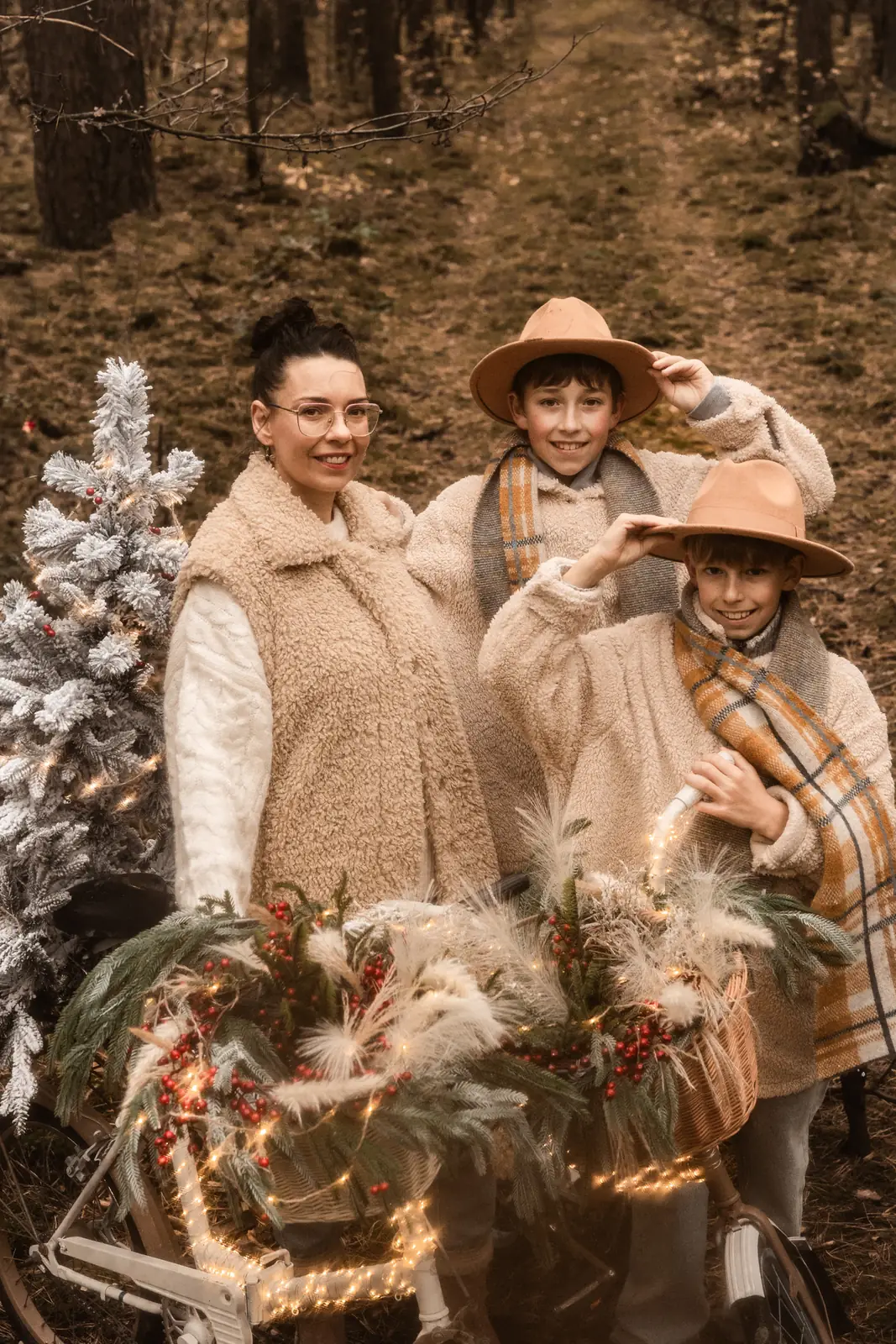 Fotografia mamy z dziećmi. Dzieci ubrane w ubrania vintage z kapeluszami. W tle świątecznej rowery z choinkami.