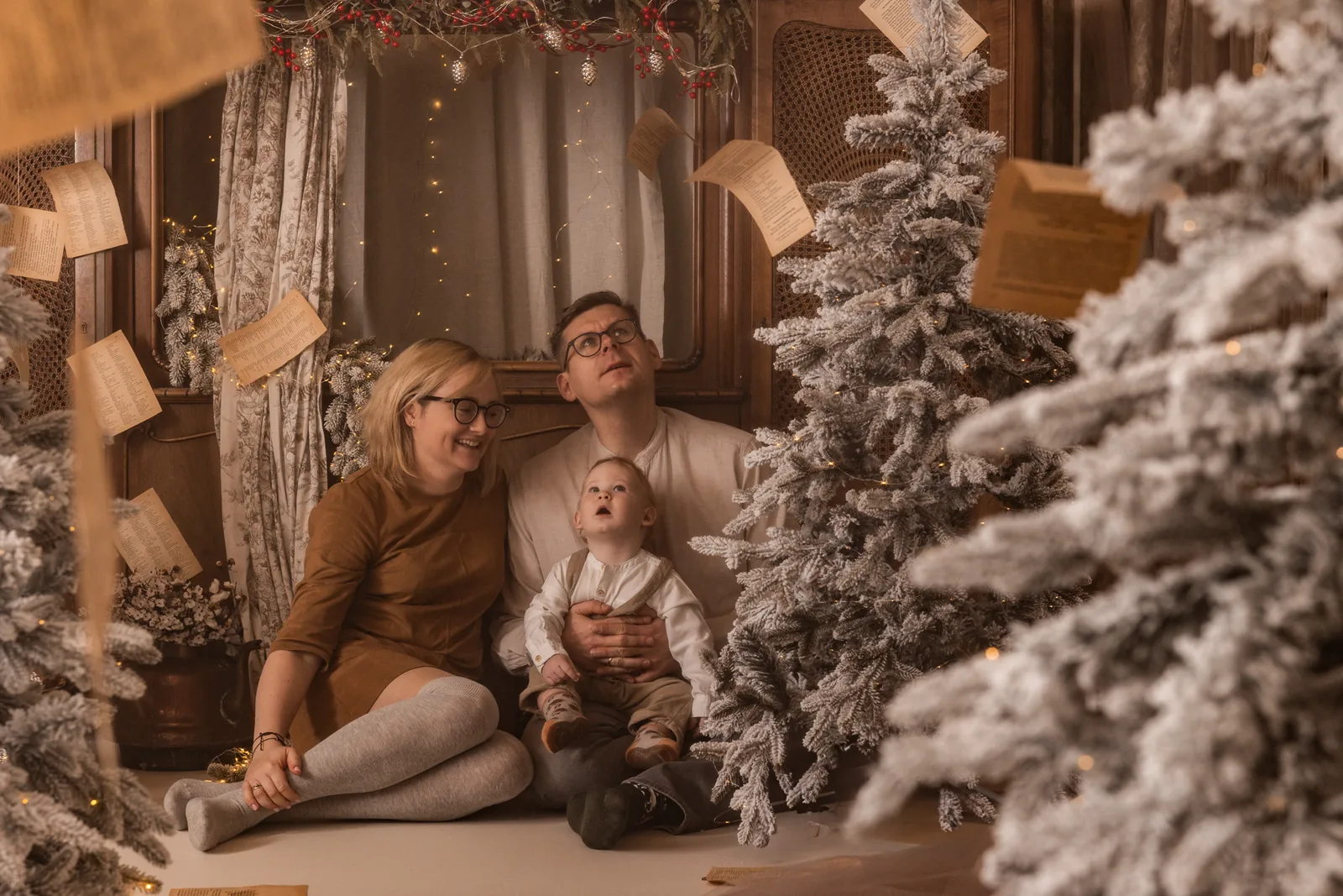 Rodzinna sesja świąteczna w studio przy śnieżno-białej choince z lampkami w stylu retro