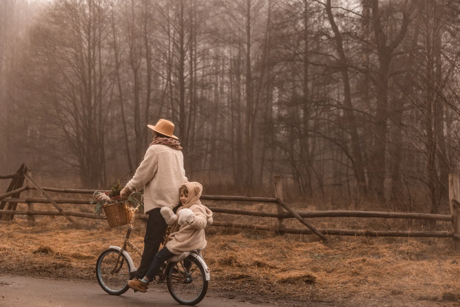 Mama z dzieckiem na świątecznym rowerze w mglistej aurze jadą przez las