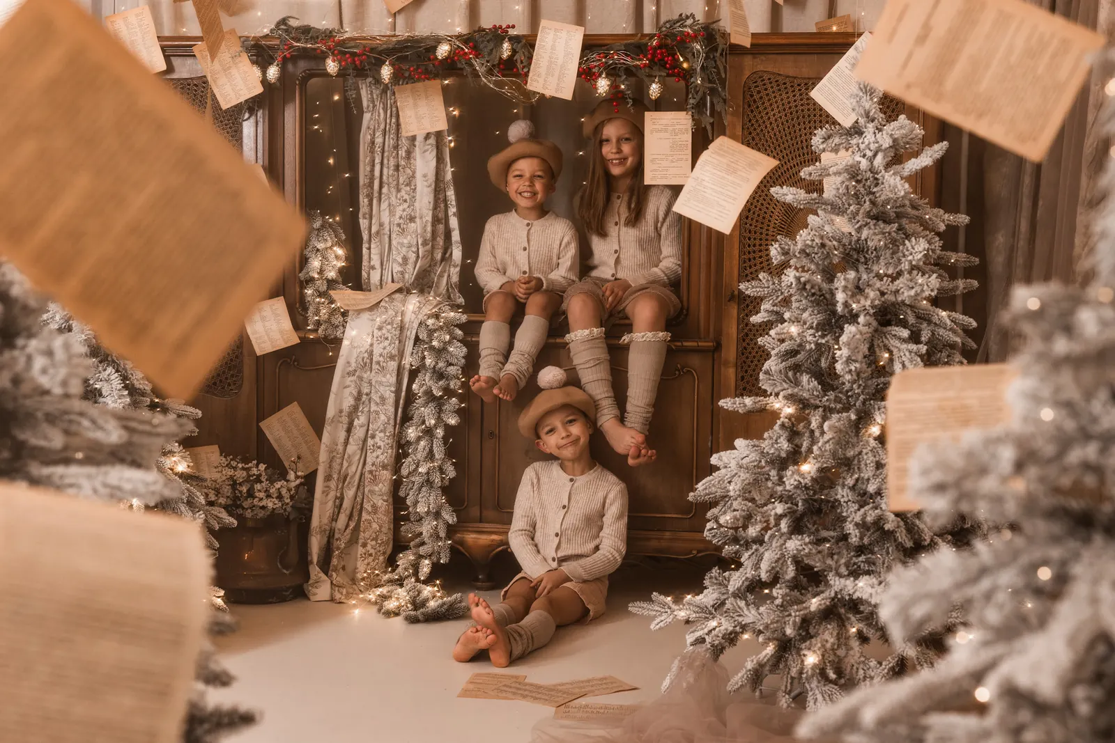 Fotografia w studio dzieci siedzących na świątecznym kredensie w stylu retro obok choinki